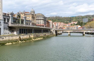 Bilbao, İspanya, 28 Mart 2024: La Concordia tren istasyonu ve Bilbao şehir merkezindeki Nervion Nehri boyunca uzanan taş kemer köprüsü. Tarihsel mimari modern şehir ve editoryal imajla çelişmektedir.