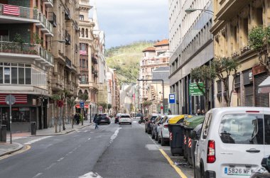 Bilbao, İspanya, 28 Mart 2024: Park halindeki arabaları, çıplak ağaçları ve Bilbao şehir merkezindeki Sagrado Corazon anıtı ile Gran Via de Don Diego Lopez Haro