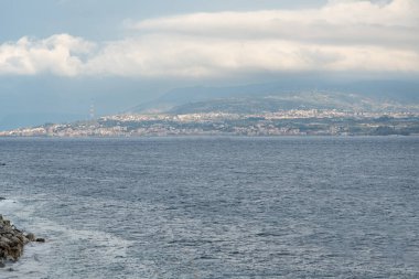 Messina, İtalya, 1 Kasım 2024: Sicilya kıyılarından Messina Boğazı 'nın karşısındaki Reggio Calabria' nın uzak görüntüsü. Tyrhenian Denizi ve iletim kulesi görünür, editoryal görüntü