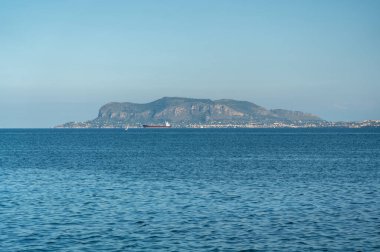 Palermo, İtalya, 18 Kasım 2024: Monte Pellegrino, Palermo yakınlarındaki sakin mavi denizin arkasında, açık bir Akdeniz altında seyreden teknelerle yükseliyor.