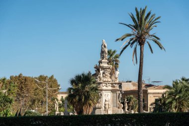 Palermo, İtalya, 18 Kasım 2024: İspanya Kralı V. Philip 'in Çeşmesi Palermo' daki Norman Sarayı yakınlarında mavi gökyüzü altında palmiye ağaçları ve barok heykeller arasında duruyor.