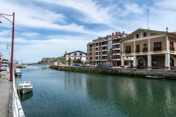Zumaia, İspanya, 4 Nisan 2024: Zumaia 'da huzurlu bir kanal, demirlemiş tekneler, deniz kıyısındaki evler ve parçalı bulutlu bir Bask gökyüzü altındaki uzak bir köprü, editoryal görüntü içerir.