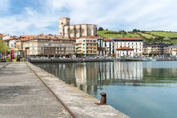 Zumaia, İspanya, 4 Nisan 2024: Zumaia tarihi rıhtım manzaraları renkli binalar ve sakin nehre yansıyan ikonik kilise, tepeler ve kasaba hayatı ile çevrili, editoryal görüntü