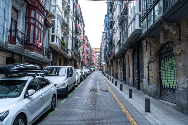 Bilbao, İspanya, 4 Nisan 2024: Park halindeki araçlar, balkonlu tarihi binalar ve eski Bilbao editoryal imajının kapalı pencereleri ile dar cadde