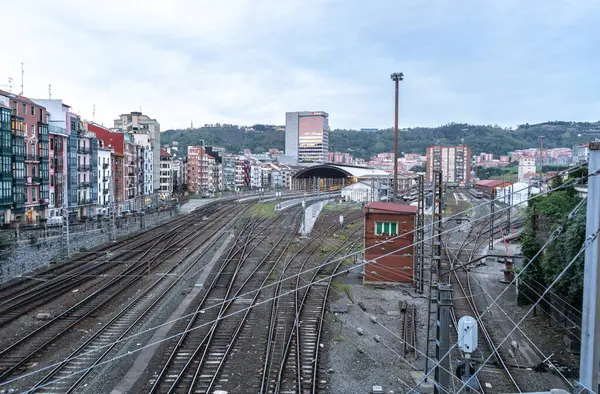 Bilbao, İspanya, 4 Nisan 2024: Bilbao Abando İstasyonu 'na giden demiryolu rayları ve arka planda yerleşim binaları ve tepeler