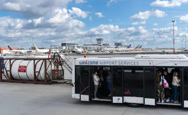 Varşova, Polonya, 6 Nisan 2024: LOT, Emirates ve Katar uçakları önünde yolcu taşıyan havaalanı servis otobüsü Varşova Chopin Havaalanı terminali, editoryal görüntü