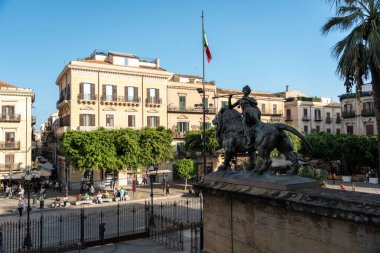 Palermo, İtalya, 18 Kasım 2024: Aslan üzerindeki bronz binici heykeli Palermo meydanına bakıyor tarihi binalar, İtalyan bayrağı ve sokak yaşamı arka planda, editoryal görüntü