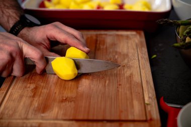 Kırsal kesim tahtasındaki tahta bıçakla patates dilimleri.