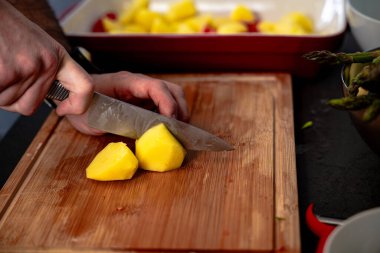 Kırsal kesim tahtasındaki tahta bıçakla patates dilimleri.