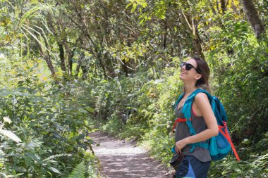 Sırt çantasıyla yemyeşil bir ormanda tek başına gezen maceraperest.