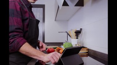Genç adam yemek pişirmeden önce bir tarif arıyor.