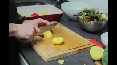 Patatesleri dilimleyip pişirme tepsisine koyuyor.