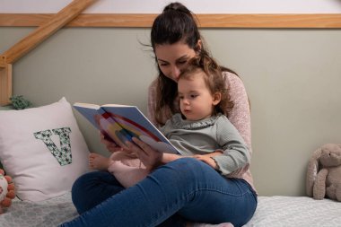 Yeni yürümeye başlayan çocuk, sıcak bir evde annesiyle birlikte okumayı öğreniyor.