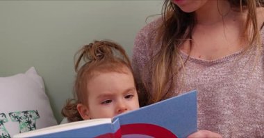Yeni yürümeye başlayan çocuk, sıcak bir evde annesiyle birlikte okumayı öğreniyor.