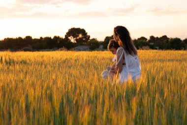 Doğadaki duygusal aile bağı, sakin bir açık hava anında altın güneş ışığıyla yıkanmış.