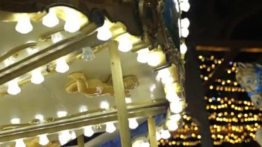 Bir yılbaşı fuarında dönen, sıcak ışıklarla aydınlatılan eski model bir atlıkarınca.