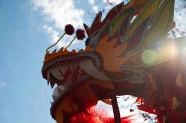 Çin ejderhası başı güneş ışığıyla mavi bir gökyüzünün altında hareket ediyor.