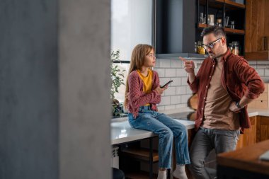 A father and his young daughter discussing her behaviors, setting up new rules at home because she is spending too much time on a smartphone. Family conflict. clipart