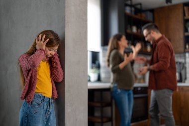Hüsrana uğramış ilkokul kızı bir kenarda durmuş, agresif ebeveynlerinin gün boyunca evde mutfakta tartıştıklarını dinliyor..