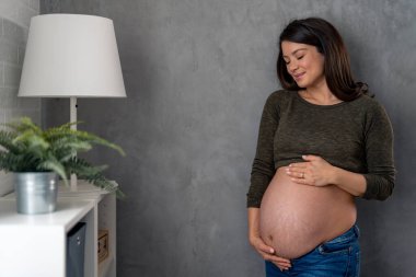 Güzel hamile kadın karnına sarılıyor, hamileliğinin tadını çıkarıyor..