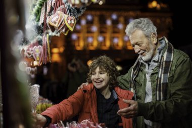 Neşeli Kafkasyalı son sınıf öğrencisi neşeli küçük torunu için neşeli, aydınlık bir market tezgahından tatlı alıyor ve güzel anılar yaratıyor..