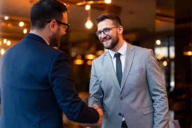 İki mutlu iş adamı yönetici yönetici iş yerinde yapılan bir toplantıda başarılı bir finansal anlaşmadan sonra el sıkışıyor..