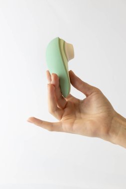 Beyaz arka planda kadın elleri süpürge vibratörü hassas nane rengi fotoğraf makinesi yetişkinler için rahatlatıcı yumurta şekilli manyetik su geçirmez.