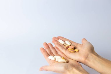 Beyaz arka planda, kadın avuçlarında farklı şekil ve renklerde haplar ve vitaminler var. İntihar düşünceleri, depresyon, sağlık hizmetleri.