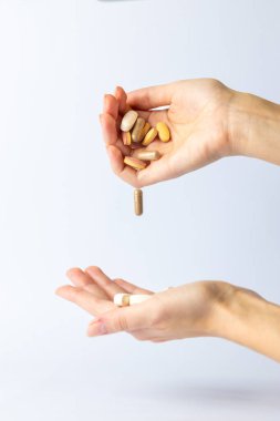 Kadın elleri, haplar ve farklı şekil ve renklerdeki vitaminler üzerindeki beyaz arka plan elden ele intihara eğilimli düşüncelerden depresyona, havada sağlık haplarına aktarılır.