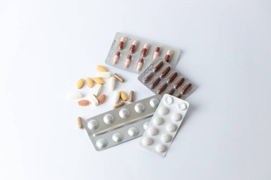 Masadaki beyaz arka planda farklı gümüş kabarcıklar, renkli kapsüller ve haplar var. İntihara meyilli düşünceler. Sağlık hizmetleri vitaminleri.