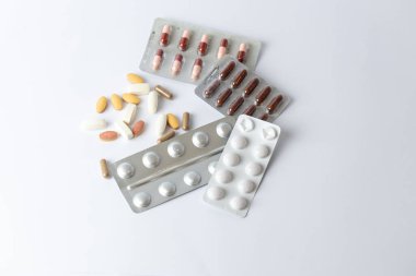 Masadaki beyaz arka planda farklı gümüş kabarcıklar, renkli kapsüller ve haplar var. İntihara meyilli düşünceler. Sağlık hizmetleri vitaminleri.