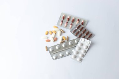 Masadaki beyaz arka planda farklı gümüş kabarcıklar, renkli kapsüller ve haplar var. İntihara meyilli düşünceler. Sağlık hizmetleri vitaminleri.