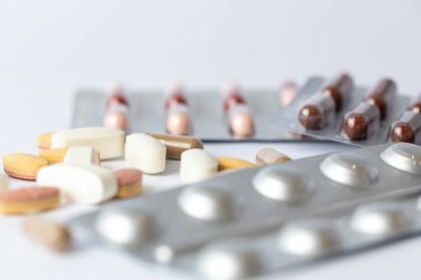 Masadaki beyaz arka plan farklı gümüş kabarcıklar renkli kapsüller ve haplarla intihar düşünceleri depresyon sağlık hizmetleri vitaminleri masada.