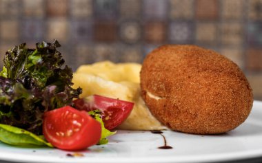 Profesyonel mutfak beyaz tabak Ukrayna mutfağı Avrupa mutfağı sağlıklı yemek Kiev pirzolası patates püresi dilimlenmiş domates ve taze salata sosu.