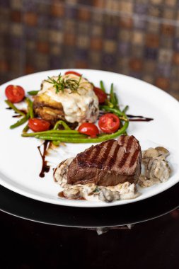 Üst düzey profesyonel mutfak beyaz tabak dana madalyonları balzamik soslu mantar soslu karaciğer ezmesi ve taze vişneli domates lokantasında biberiye filizleri servis ediliyor.