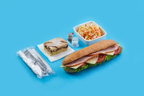 Yumuşak mavi arka planda tek kullanımlık yemek takımı var. Atıştırmalıklar için. Tuz ve biberli salata sandviçi, omlet ve domatesli tatlı turta.