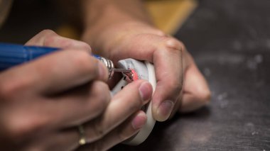 Profesyonel bir laboratuara yakın plan diş imalatı, takma dişler ve kaplamalar, bir usta alçı kalıbındaki metal pları ayarlamak için bir değirmen kullanır, bireysel üretim