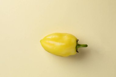 Açık sarı arka planda bulunan bir nesnenin yakın plan fotoğrafı taze yıkanmış açık sarı bir dolma biber ile birlikte bir kök güz meyvesi sağlıklı vejetaryen besin birçok yararlı vitamin içerir.