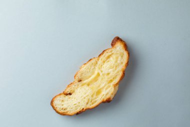 Açık mavi arkaplanda bulunan bir nesnenin yakın plan fotoğrafı dilimlenmiş bir parça beyaz ekmek fırını ürünü Fransız ekmeği ile ilgili.