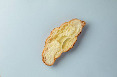 Açık mavi arkaplanda bulunan bir nesnenin yakın plan fotoğrafı dilimlenmiş bir parça beyaz ekmek fırını ürünü Fransız ekmeği ile ilgili.