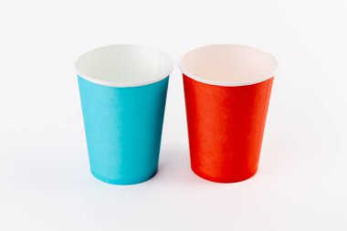 Beyaz zemin üzerinde iki kağıt bardak kahve ve çay için kırmızı ve mavi masa eşyalarıyla boyanmış geziler, eğlence ve piknik bardakları su geçirmez.