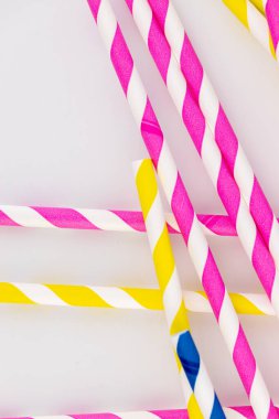 Beyaz arka planda kokteyller ve farklı içecekler için birçok renkli kağıt şeritli tüpler vardır. Pembe sarı ve mavi şeritli tüpler bahar havası.