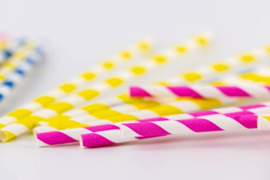 Beyaz arka planda kokteyller ve farklı içecekler için birçok renkli kağıt şeritli tüpler vardır. Pembe sarı ve mavi şeritli tüpler bahar havası.