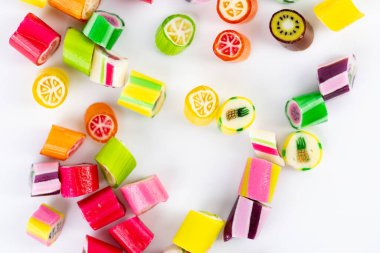 Farklı tat ve kalıplara sahip küçük, çok renkli şeker karamellerinin beyaz arka planına yakın plan uzanır. Çocukların en sevdiği şekerler kan şekerinin aşırı ağırlığa maruz kalma riski çok yüksektir.