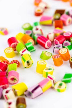 Farklı tat ve kalıplara sahip küçük, çok renkli şeker karamellerinin beyaz arka planına yakın plan uzanır. Çocukların en sevdiği şekerler kan şekerinin aşırı ağırlığa maruz kalma riski çok yüksektir.