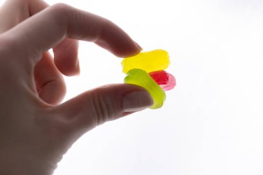 Beyaz arka planda kadınların parmaklarında karamel şekerler yeşil pembe sarılar şeker hastalığının çok fazla gelişimi ve çocuklar için tatlı