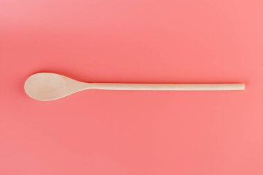 Yumuşak pembe arka planda, yeni mutfak aydınlatması, ahşap çatal bıçaklar, kaşık şekilleri, doğal ahşap kaplama spatulaları, el yapımı farklı kullanım şekilleri bulunur.