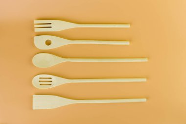 Üst çekimde yumuşak sarı arka planda farklı şekillerde mutfak aydınlığı ahşap çatal bıçaklar var. Teflon kaplama doğal ahşap farklı kullanım şekilleri için spatula.