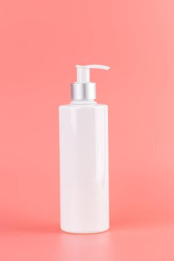 Yumuşak pembe arka plan üzerine yakın plan beyaz parlak şişe ile kozmetik güzellik endüstrisi için minimalist kap Sıvı depolama