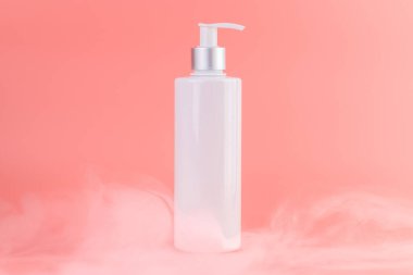 Yumuşak pembe arka plan üzerine yakın plan beyaz parlak şişe ile kozmetik güzellik endüstrisi için minimalist kap Sıvı hava deposu açık beyaz bir sis içinde duruyor
